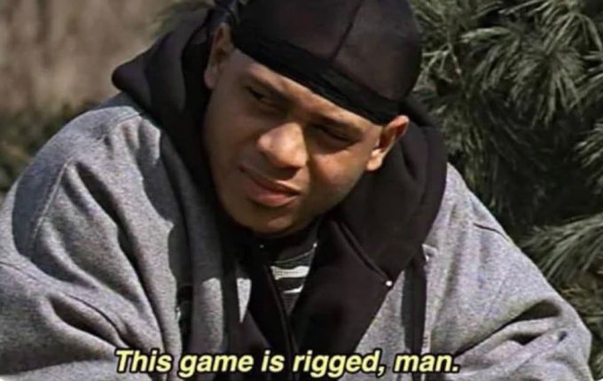 A meme featuring a young man in a black durag and gray hoodie looking skeptical, with the caption 'This game is rigged, man.'