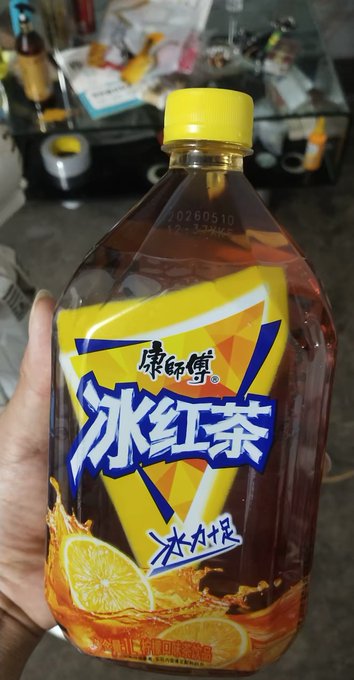 A hand holds a bottle of Master Kong (康师傅) iced lemon black tea (冰红茶, 冰力十足) with a date code "20260510" visible on the cap seal, representing the refreshing "仙品" cold iced tea mentioned in the post as a way to cool down during the humid, rainy post-立秋 weather.