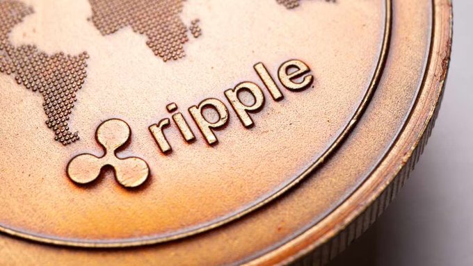 A close-up of a copper-colored Ripple (XRP) cryptocurrency coin displaying the Ripple logo and a world map design.