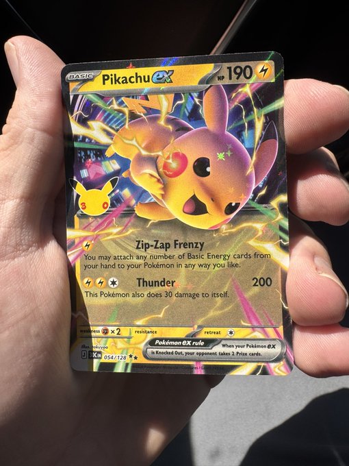 A hand holding a holographic 'Pikachu ex' Pokémon trading card from the Prismatic Evolutions set, featuring its Zip-Zap Frenzy and Thunder attacks.