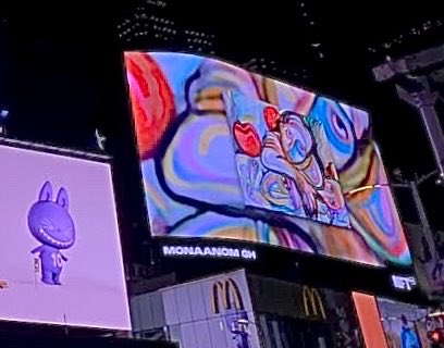 A nighttime view of a large illuminated billboard displaying colorful abstract NFT artwork with 'MONAANDOM GM' written on it, next to a purple screen showing a cartoon rabbit character, with a McDonald's sign visible below.