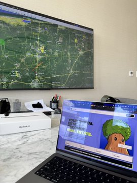 A desk setup featuring a large monitor displaying a weather radar map and a laptop open to the National Oceanic and Atmospheric Administration (NOAA) website.