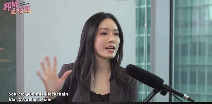 A woman speaking into a microphone in an interview setting, with Chinese text overlay and sources listed as '@Bonnie Blockchain' and '@WuBlockchain'.