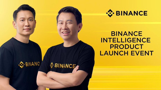 Two men wearing black Binance-branded t-shirts pose against a bright yellow background, with one smiling with arms crossed. The image promotes the "BINANCE INTELLIGENCE PRODUCT LAUNCH EVENT" and visually represents Binance's expansion into AI, aligning with the announcement of @binance Intelligence, which unifies Agent OS, Binance AI for market research, and other AI-powered experiences under one platform.