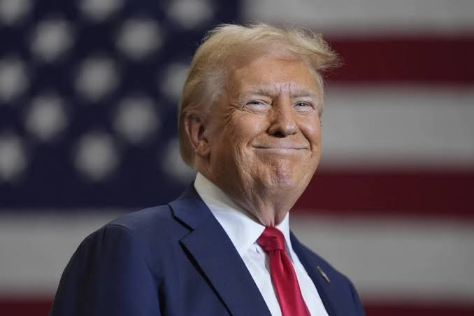Former President Donald Trump smiles in front of the American flag, a symbolic backdrop for the news that the White House is meeting with crypto executives next week.
