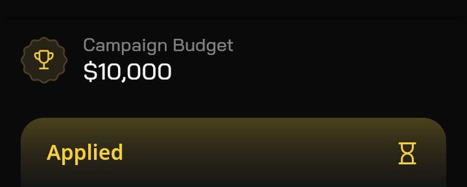 The image shows a dark-themed interface displaying "Campaign Budget $10,000" with a trophy icon, alongside an "Applied" status with a gold border, indicating a completed campaign action on Wallchain. The "Applied" status paired with the context suggests the budget was successfully submitted, reinforcing the post's hint that the project is in high demand and reducing the suggested price wouldn't make participation easier.