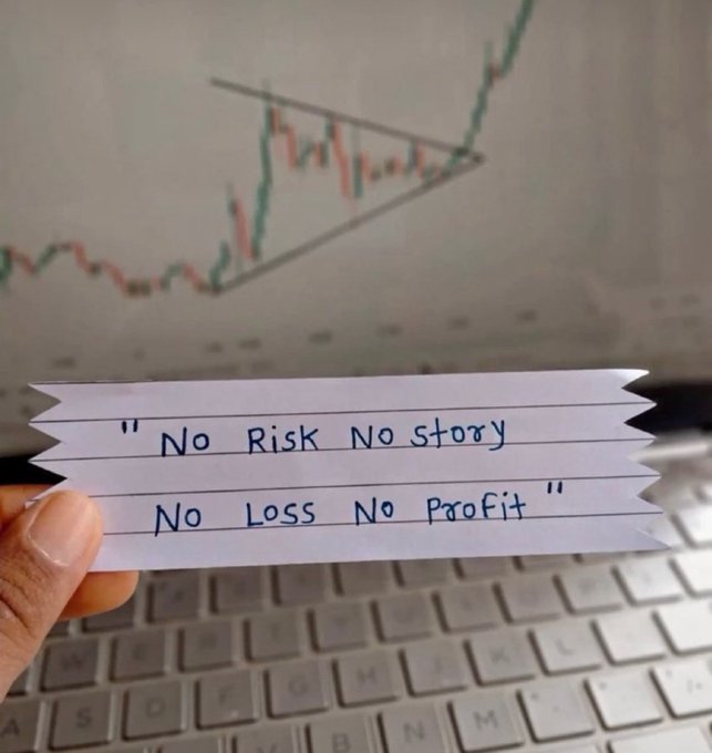 A hand holds a torn piece of lined paper reading '"No Risk No Story No Loss No Profit"' in front of a laptop screen displaying a financial candlestick chart with a drawn triangle pattern.
