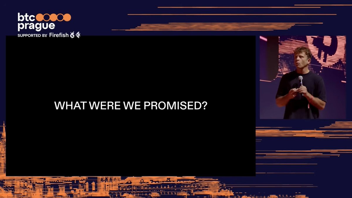 The image features a large screen with a man standing behind it, giving a speech or presentation. The background of the image has orange and blue stripes, creating an interesting visual effect. There are also some words written in white text that read "What were we promised?" This suggests that the speaker is addressing a question about promises made by Bitcoin or cryptocurrency.