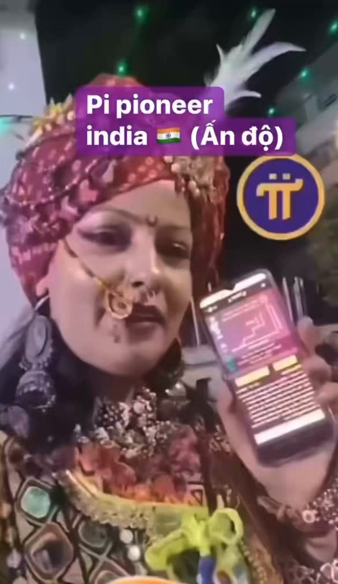 The image features a woman dressed in traditional Indian attire, wearing a red turban and a gold headpiece with flowers. She holds up her cell phone, which displays an image of a white square with black text that reads "Pi Network! Pi Pioneer India". The woman is positioned against the backdrop of a building, suggesting she might be at an event or gathering in India.

The post includes a caption that reads "Pi Network! Pi Pioneer India", indicating that the image was taken during an event related to Pi Network and Pi Pioneer India.