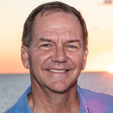 A smiling middle-aged man in a blue shirt poses for a portrait against a sunset ocean backdrop, visually representing the macro trader referenced in the post. The caption below his image reveals he is Paul Tudor Jones, a renowned investor who recently disclosed holding 688,529 shares of iShares Bitcoin Trust (IBIT) valued at $23 million.