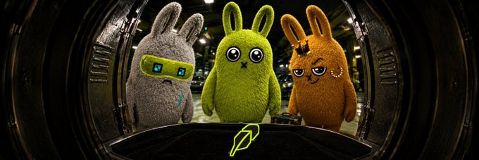 Three plush bunny characters (gray with goggles, green, and orange with an eye patch) peer out from a metallic chamber, with the "BunnyHood" logo displayed below, illustrating the brand opening its doors for waitlist access to upcoming products.