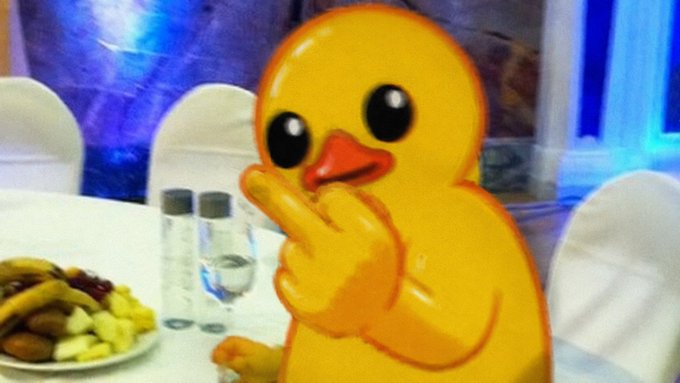 A cartoon yellow duck with big black eyes sits at a table with a plate of fruit and a water bottle, making a pointing gesture toward the viewer. The image is paired with a bullish prediction that $UTYA will reach a $10 billion market cap this cycle, using the duck as a meme to emphasize confidence in the price target.