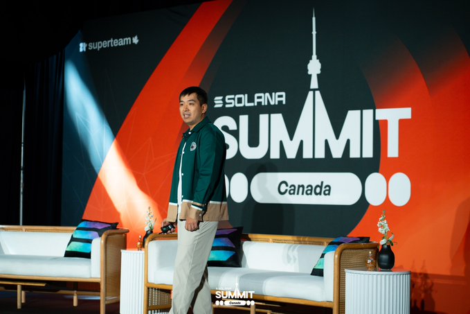 A man poses on stage at the 'Solana Summit Canada' event with a 'superteam' logo visible on the backdrop.