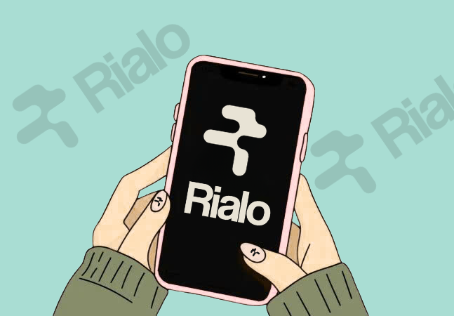 An illustration of hands holding a smartphone displaying the 'Rialo' app logo on its screen, with 'Rialo' watermarks visible in the background.