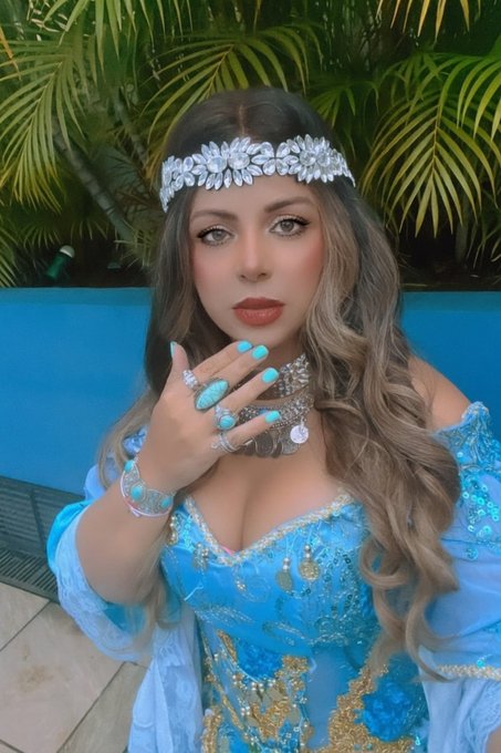 A glamorous woman wearing a sparkling blue embellished outfit, silver headpiece, and crystal jewelry poses against tropical greenery. The image appears unrelated to the post about a Polymarket bet on alien abductions during a Brazil vs. Scotland World Cup game.
