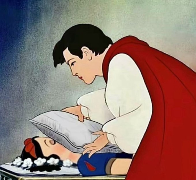 A classic Disney animation still of the Prince discovering Snow White asleep on the bed, lifting a pillow above her.