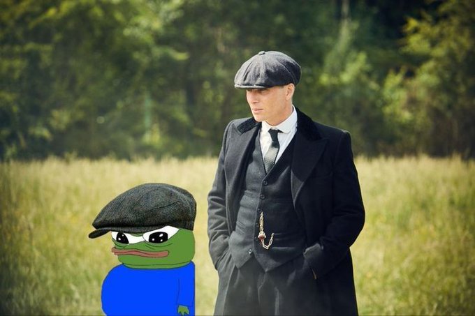A man in a flat cap and suit—reminiscent of Tommy Shelby from *Peaky Blinders*—stands in a field while an angry Pepe the Frog wearing a matching flat cap glares from beside him. The grim pairing visually represents the fear of heading outside with a decimated portfolio, where even the grass poses a threat rather than offering comfort.