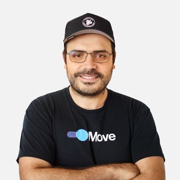 Portrait photo of a smiling man with glasses and a beard wearing a black baseball cap and a black t-shirt with the 'ChainMove' logo, standing with arms crossed against a light gray background.