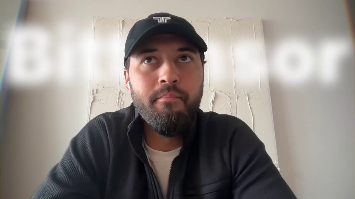 The image features a man wearing a black baseball cap with the word "Bitch" written on it. He has a beard and is sitting down, possibly at a desk or table. The background of the image is white, which contrasts with the man's dark attire. There are also some words visible in the image that seem to be related to the post about institutional investors.