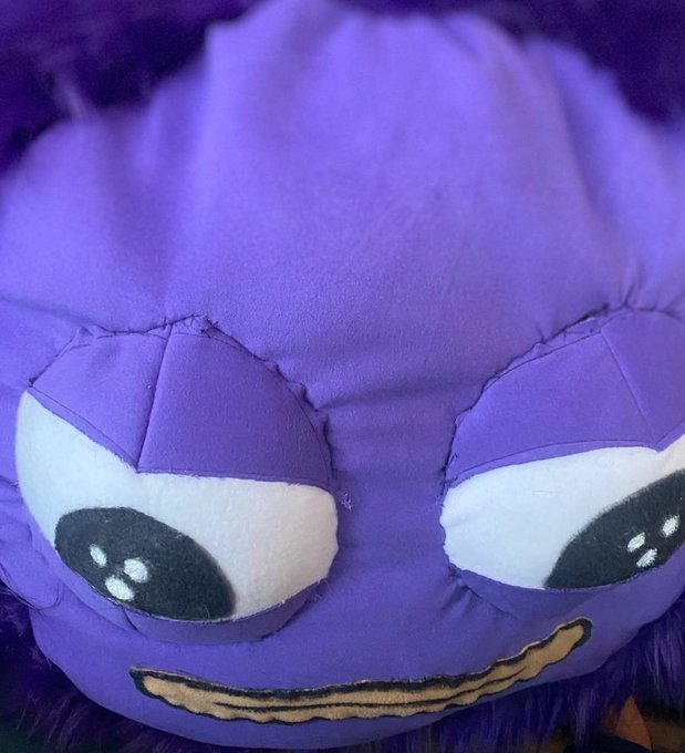 A close-up of a purple plush character's angry face with furrowed white-and-black eyebrows and a small frowning mouth, paired with a caption urging viewers to pay attention to the Monad blockchain project and its features like privacy, AI, decentralization, and EVM performance. The plush's stern expression visually reinforces the post's frustrated, wake-up-call tone toward those ignoring Monad.