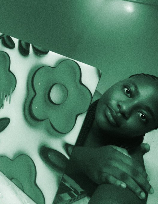 A green-tinted photo of a person resting their chin on their hand next to a board with flower-shaped pieces.