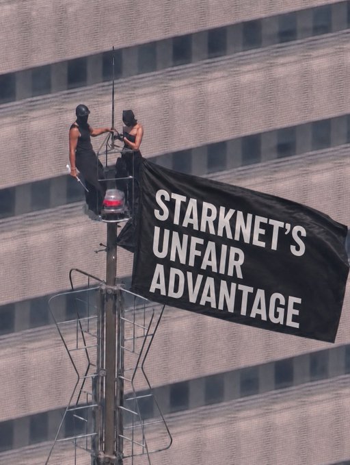 Two people stand atop a tall metal structure unfurling a black banner reading "STARKNET'S UNFAIR ADVANTAGE" against a gray building facade. The image visually proclaims the bold claim made in the post, which announces Starknet's roadmap toward post-quantum security before the arrival of quantum computing's "Q-day."