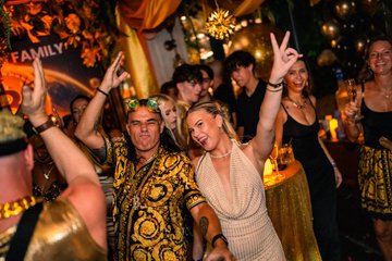 A group of people are enjoying themselves at a lively party, with the word "FAMILY" visible in the background and a Bitcoin symbol in the bottom left corner, aligning with the post's description of a fun Bitcoin-themed gathering.