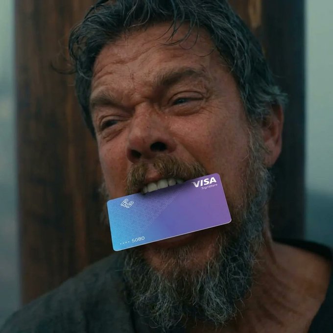 A rugged, bearded man bites down on a Visa Signature credit card, protectively clutching the 3% cashback reward he's determined to keep.