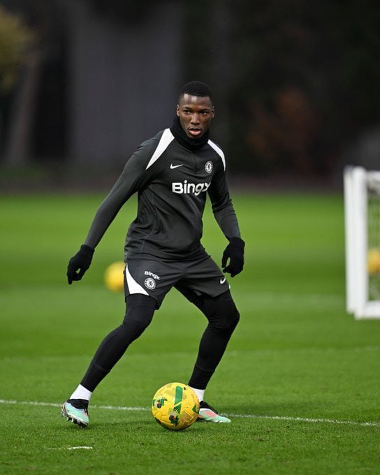 Soccer player Ousmane Diomande in a black Chelsea training kit (Bingx sponsor) practicing ball control on a training pitch.