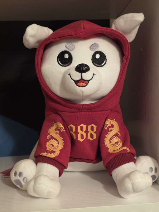 A white plush dog toy wearing a red hoodie featuring golden dragon designs on the sleeves and the number '888' in gold on the chest.
