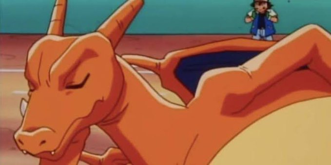 An anime still showing an orange dragon-like creature (Charizard) lying on the ground with eyes closed, while a small character stands in the background.