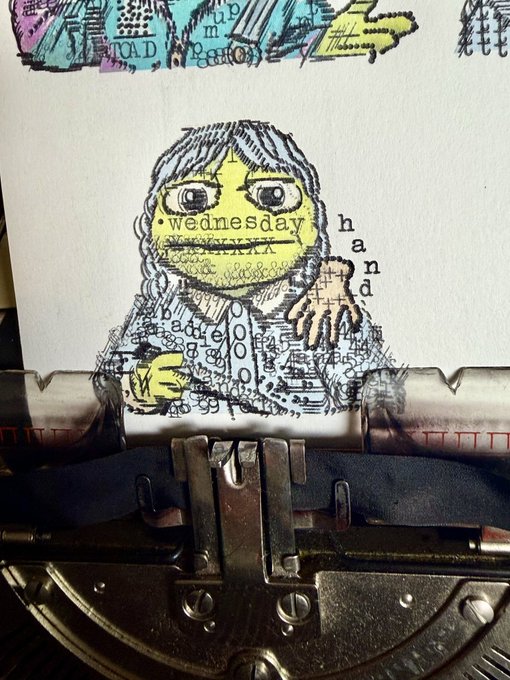 An artistic collage showing a typed paper with a drawing of a girl containing the word 'wednesday', placed on top of a vintage typewriter.