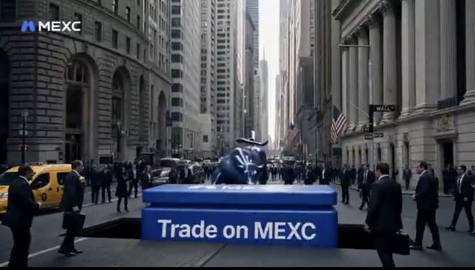 A bull statue stands atop a blue "Trade on MEXC" platform on a busy Wall Street street, surrounded by suited businessmen, while the MEXC logo appears in the top-left corner.

The image illustrates the post's message by depicting the iconic Wall Street bull alongside MEXC's branding, visually contrasting traditional market barriers with accessible crypto trading opportunities.