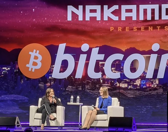 Hester Peirce, often known as "Crypto Mom," appears on stage at a "Nakamoto Presents: Bitcoin" event in conversation with another speaker, discussing her tenure at the SEC where she championed regulatory clarity for digital assets and proposed her notable safe harbor framework for crypto.