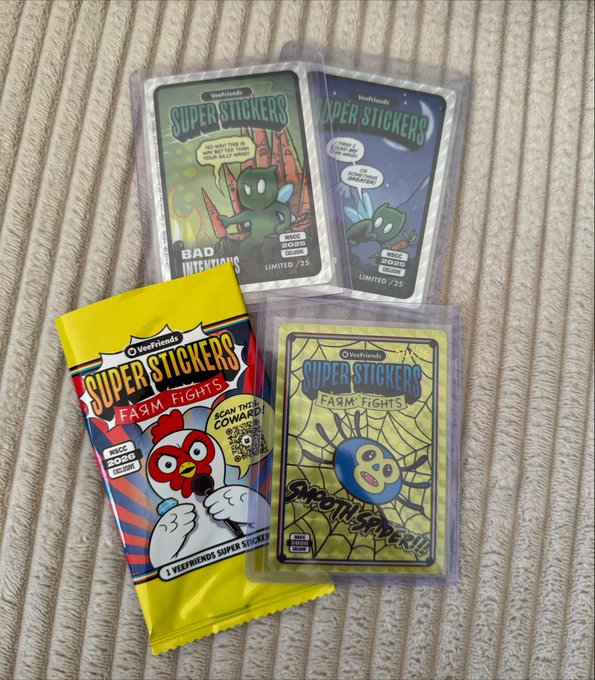 Three packs of Veefriends 'Super Stickers' featuring cartoon characters and themes like 'Farm Fights' and 'Bad Invitations', resting on a ribbed fabric surface.