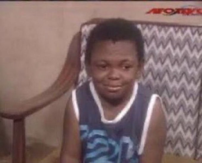 A low-quality TV screenshot of a young boy in a blue basketball jersey sitting on a patterned couch, with an APOΓKO logo visible in the corner.