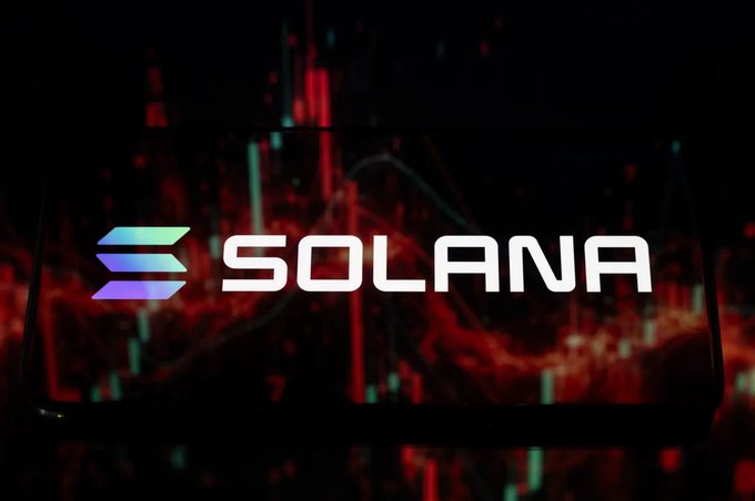The Solana cryptocurrency logo displayed on a smartphone screen with a red and dark candlestick chart background, suggesting trading or market activity.