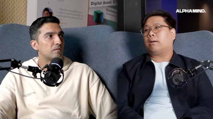 Two men sit on a couch with microphones in what appears to be a podcast setting, with an 'ALPHAMIND.' logo visible in the upper right corner.