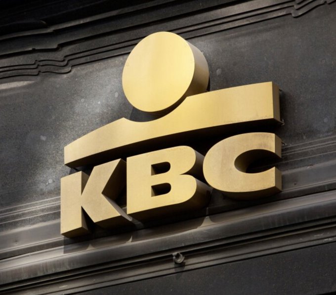 A golden KBC bank logo is mounted on a dark, weathered surface, representing the Belgian financial institution that has officially launched Bitcoin trading services for its 4 million clients, marking a significant step in mainstream cryptocurrency adoption.