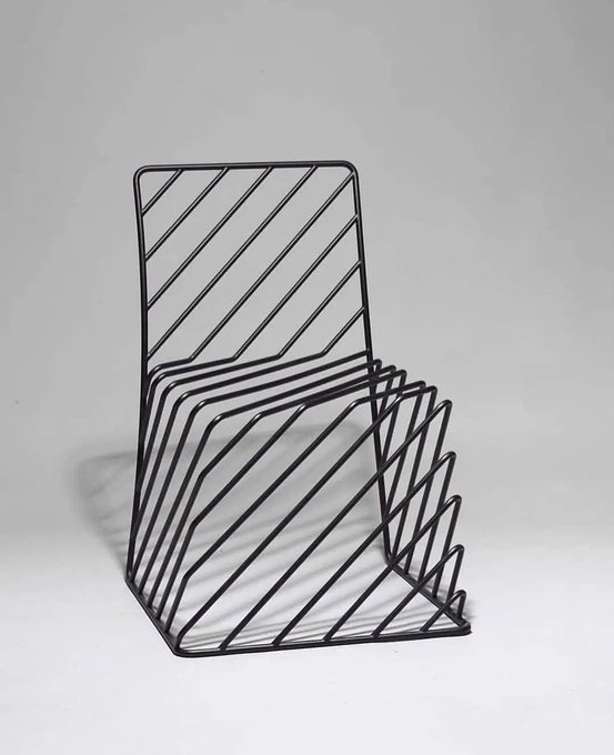 A black wire file or magazine rack with diagonal slats, photographed against a plain white background.