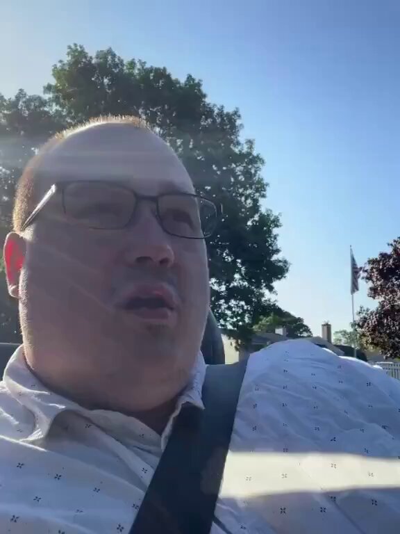 The image shows a man wearing glasses, sitting inside a car with his head resting against the window. He appears to be looking out of the car window or possibly at someone outside. The photo has been edited to include text that reads "loose convictions held strongly". This could potentially be an indication of the man's personal beliefs and opinions on certain matters, which he may feel strongly about.

The image also contains a flag in the background, suggesting that they might be driving near or through a country with a national flag. The presence of this flag adds context to the scene and emphasizes the idea of loose convictions being held strongly by the man inside the car.