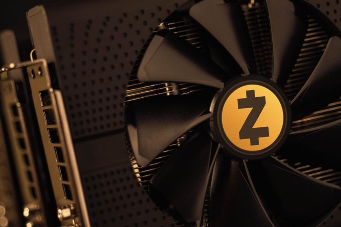 A close-up photograph of a computer cooling fan featuring a gold circular center with the Zcash 'Z' logo, mounted on a dark perforated surface.