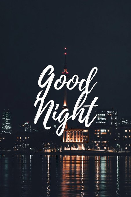 A nighttime cityscape featuring a tall illuminated tower with red lights at its peak, reflected in the water below, overlaid with elegant white script text reading "Good Night".