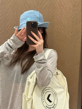 A person takes a mirror selfie wearing a light blue denim cap while holding a phone, with a cream-colored ball bag featuring a black "C" logo and text reading "FROM DREAM" visible on their shoulder, matching the BG Wallet commemorative gift box items mentioned in the post.