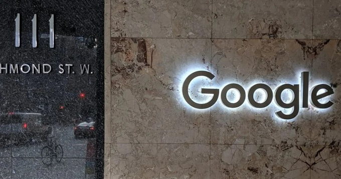 An exterior shot of a building with an illuminated "Google" sign mounted on a stone wall, with "111" and "RICHMOND ST. W." visible in a window.