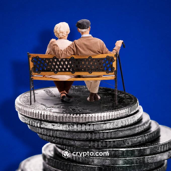 An elderly couple sits together on a small bench atop a stack of oversized silver coins branded with the "crypto.com" logo, symbolizing the financial foundation needed for a secure retirement. The image reinforces the message that retirement depends on having sufficient assets—likely accumulated through investments—to sustain one's lifestyle.