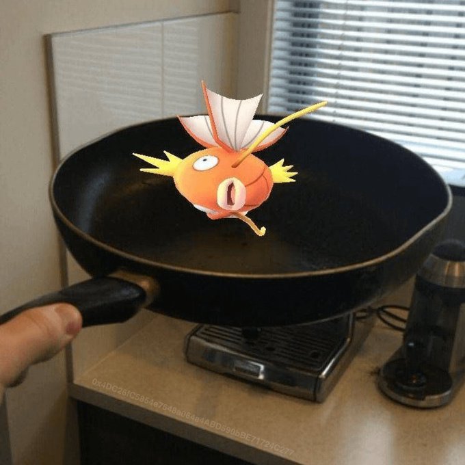 A hand holds a frying pan with a Magikarp from Pokémon levitating inside it, appearing as if the fish is being cooked mid-air. The "meal prep" pun plays on Pokémon trainer "prep" — using a pan with a Pokémon, complete with a visible code "0x4DC26FC5854e794Baa64a64ABD59bbBE71724C277" at the bottom of the counter.