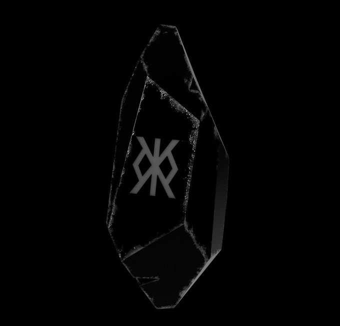 A dark, angular crystal or rock formation against a black background featuring a geometric logo etched into its center.