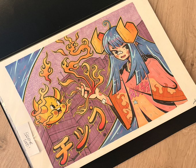 An art book featuring an anime-style character with blue hair in a kimono holding flames, alongside a yellow flame creature, with Japanese text including 'クリツ' visible.