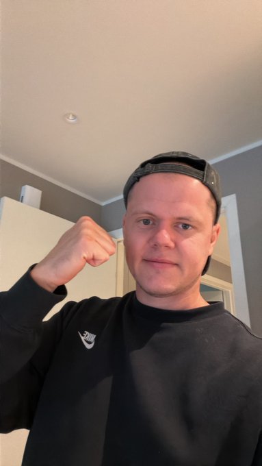 A man wearing a black Nike sweatshirt and backward cap flexes his fist in a confident, ready-to-trade pose, channeling bullish energy. The image visually reinforces the post's hyped "have a nice trading day" message, with the flexed arm symbolizing strength in anticipation of CPI's impact on the $USELESS ticker.